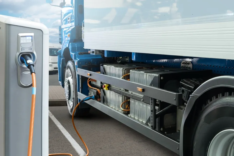Electric 18-wheeler truck plugged into electric charger.